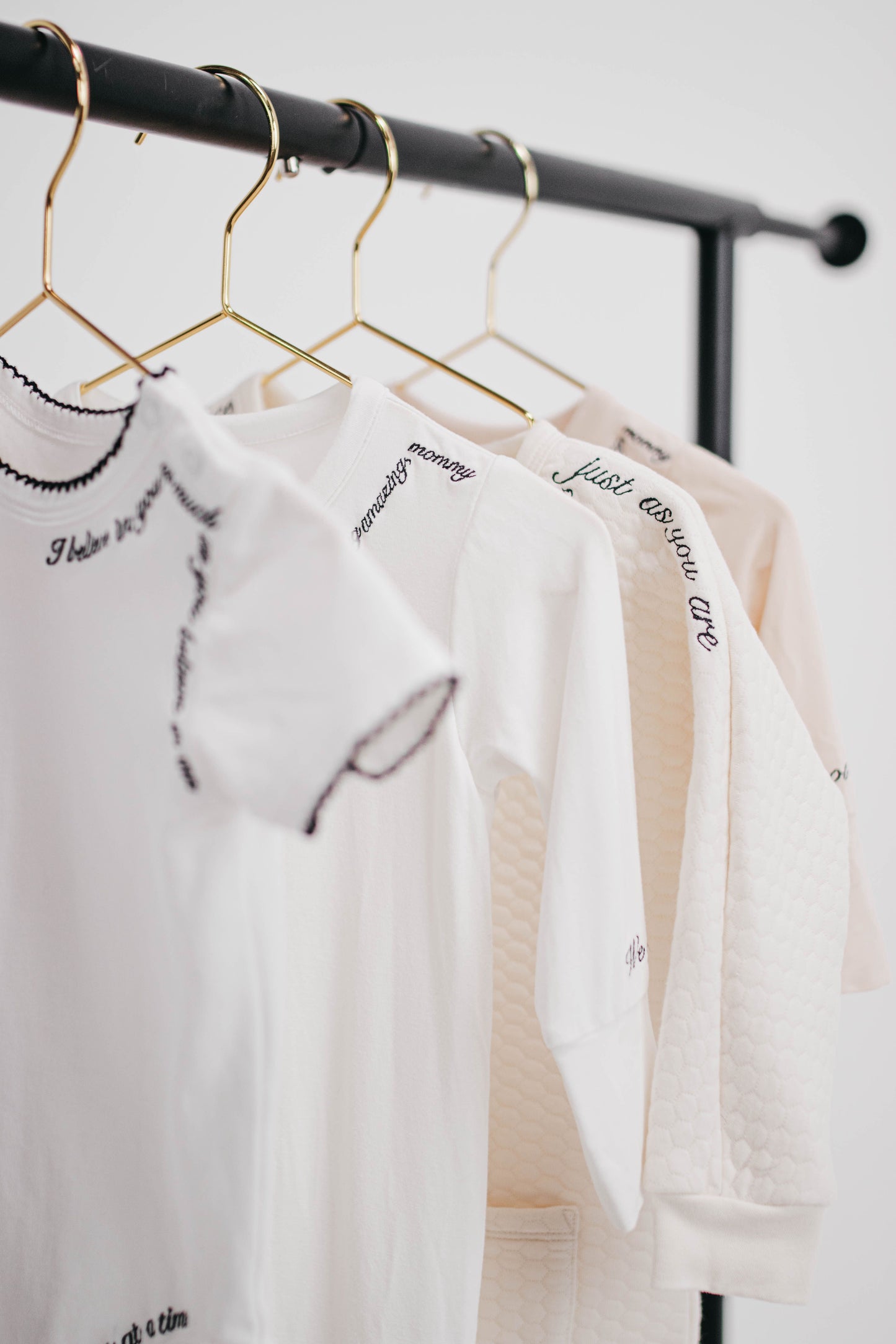 White t-shirts with text on hangers against a white background